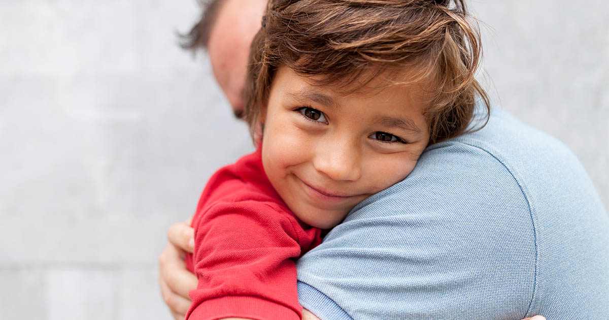 A child smiling on his dad's shoulder