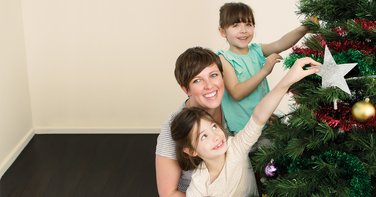 Decorations being placed on a Christmas tree by a family